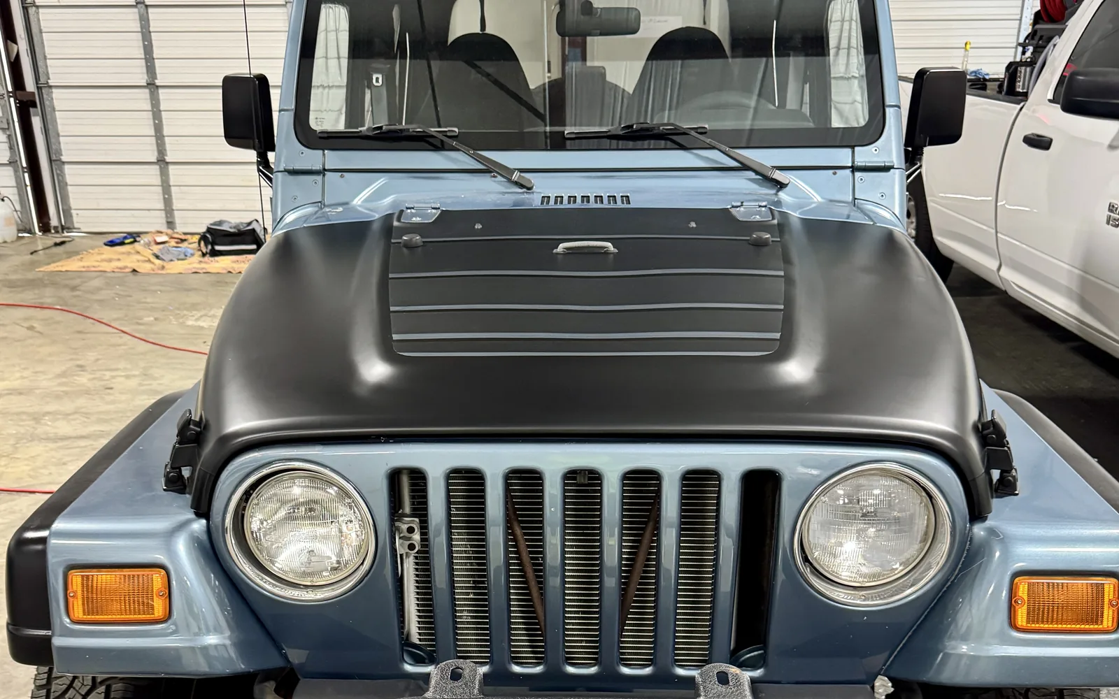 Jeep Wrangler with a black accent hood wrap over blue factory paint